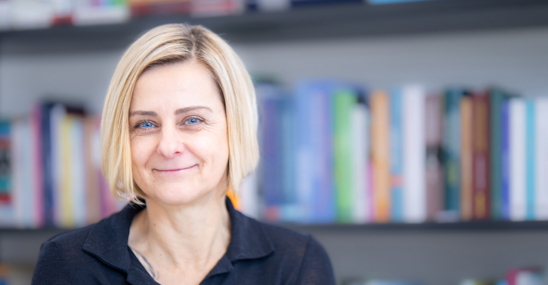 Psychotherapeutin Christiane Brazda lächelt vor einer Bücherwand in die Kamera